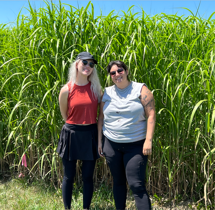 Kelly Anne Tucker and Alison Marklein stand in front of a field of corn at an Eion research site